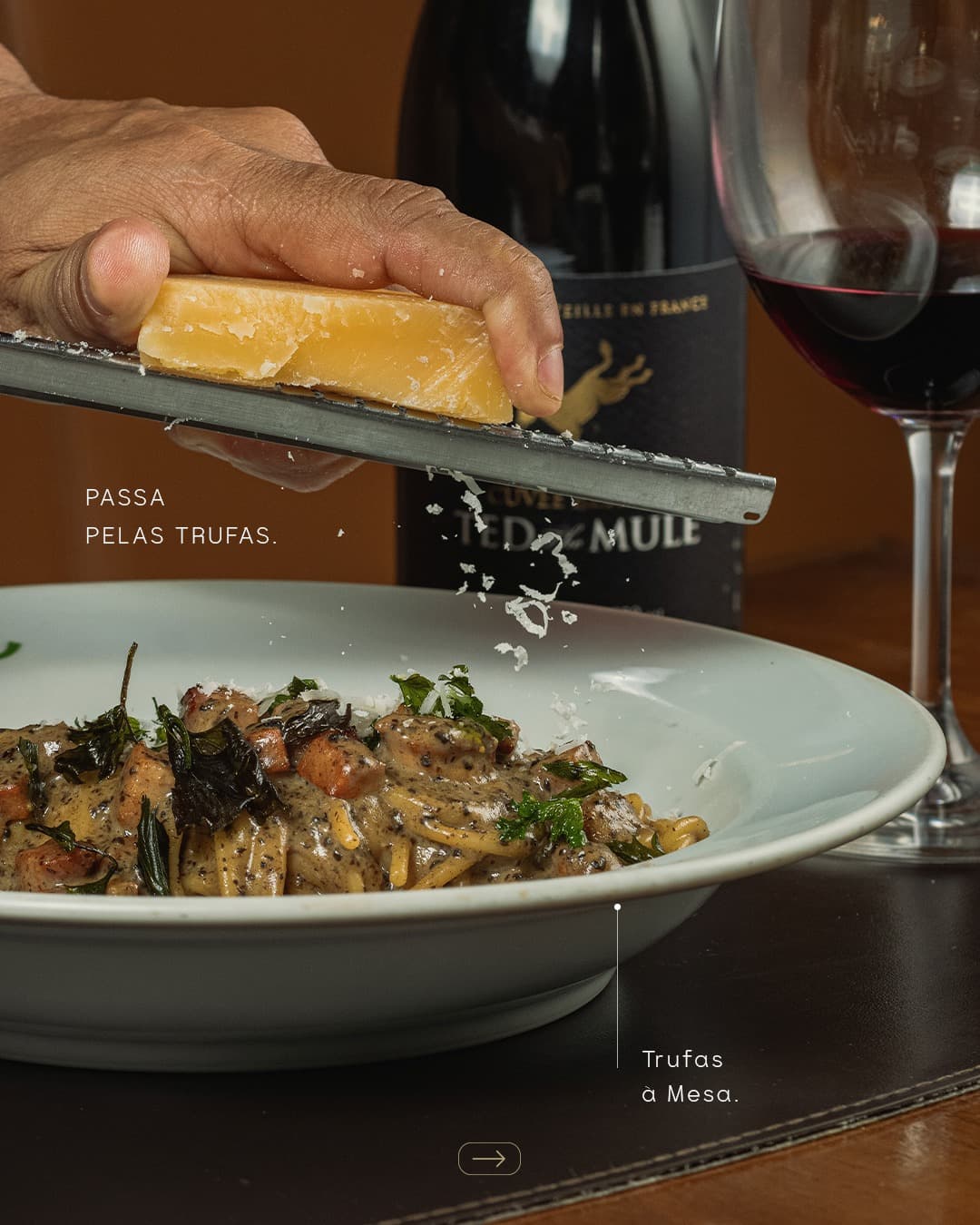 Queijo sendo ralado sobre massa trufada, ao lado de uma taça de vinho tinto, com a legenda “Passa pelas trufas”
